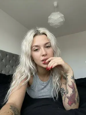 Casual smartphone photo of a tattooed woman in a bedroom