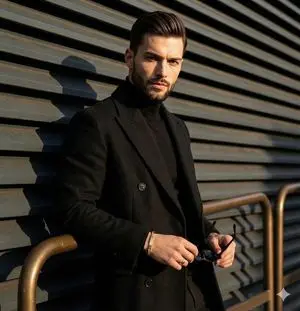 High-contrast editorial portrait of a man leaning on a rail