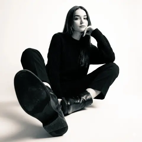 High-contrast black-and-white studio photo of a woman seated on